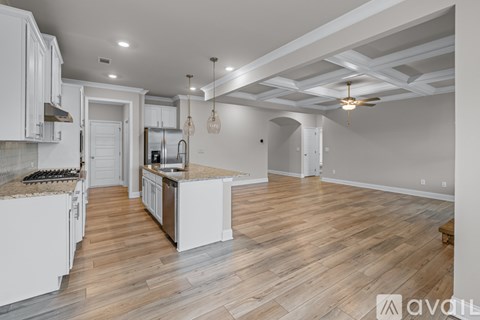 A kitchen with white cabinets and a wooden floor.