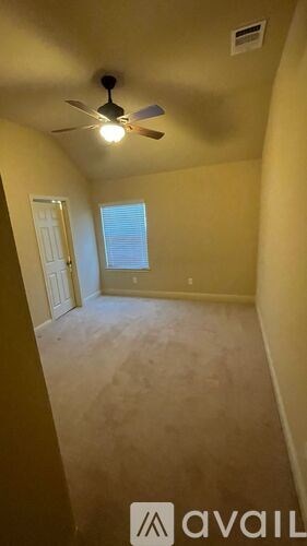A room with a ceiling fan and a door leading to another room.