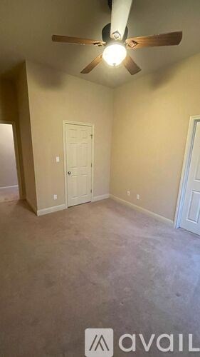 A room with a ceiling fan and a door.