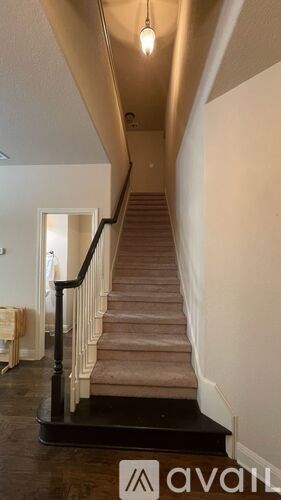 A staircase with a beige carpet and black handrail.