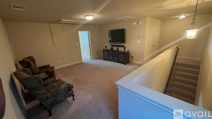 A living room with a couch, television, and stairs.