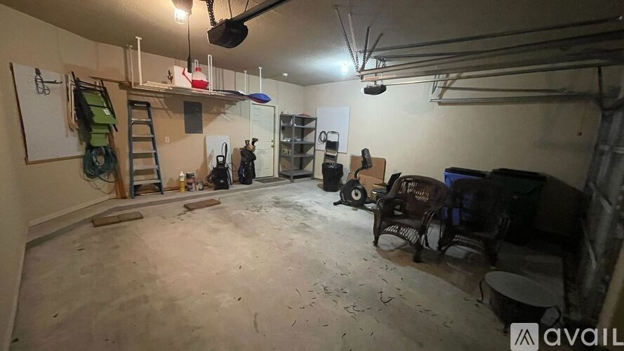 A room with a ladder, a fan, and some tools.