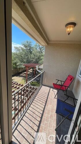 A balcony with a red chair and a table.