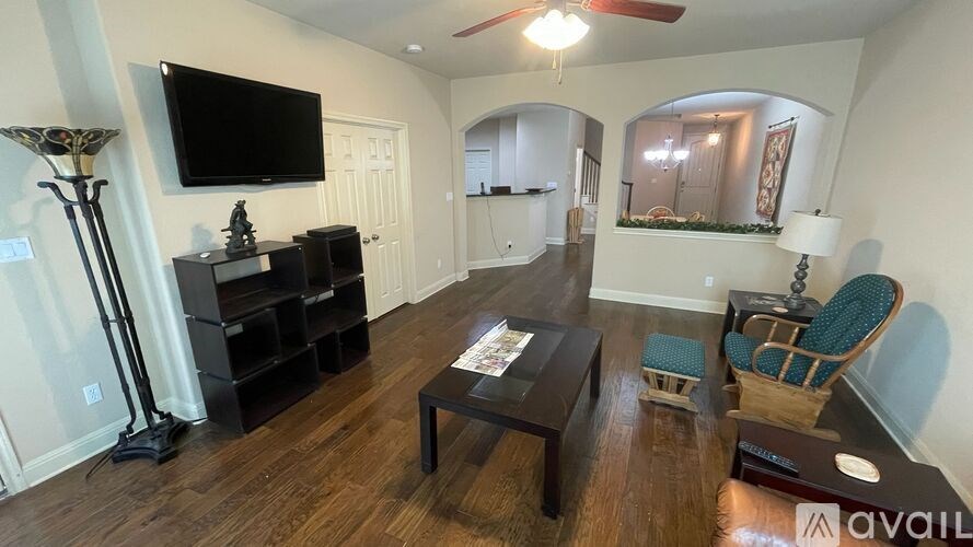 A living room with a black TV on the wall and a wooden floor.
