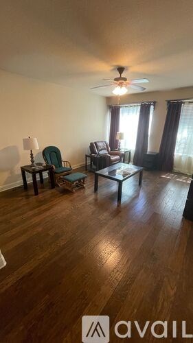 A living room with a wooden floor and a ceiling fan.