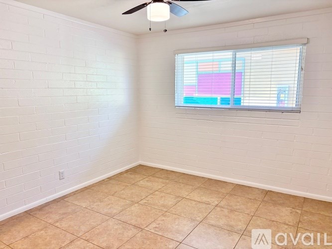 A room with a fan and a window with blinds.