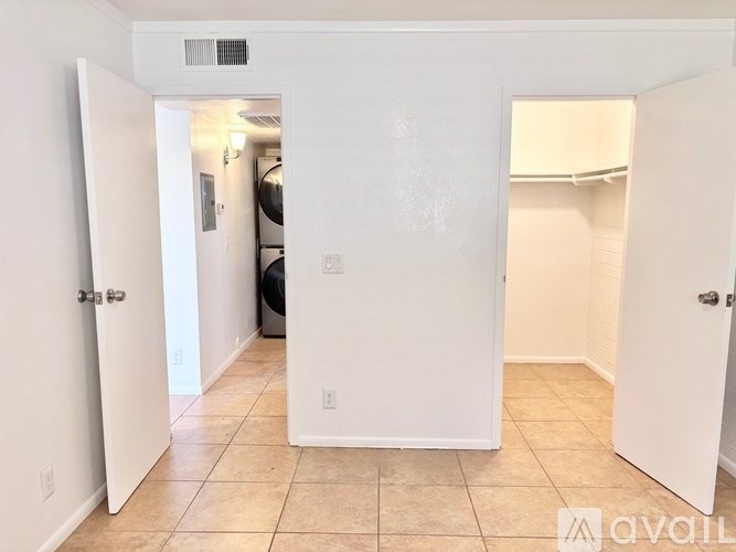 A white room with a tiled floor and a washing machine in the corner.