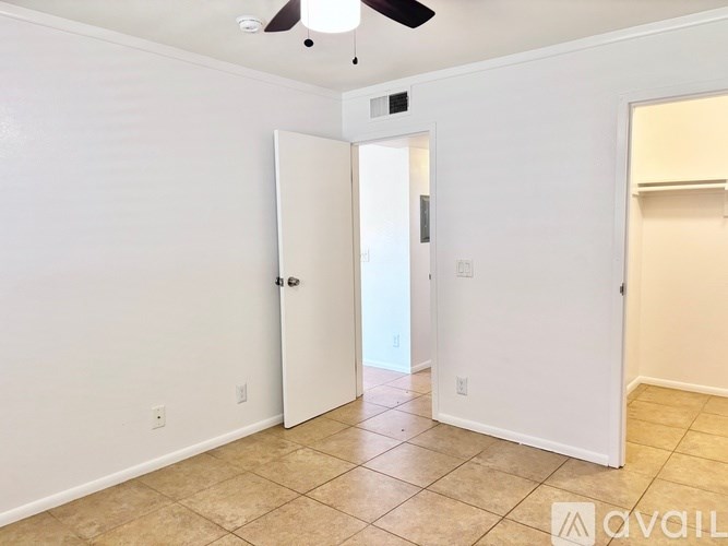 A room with a ceiling fan and a door leading to another room.