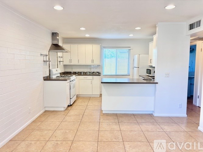 A kitchen with white cabinets and appliances is available for rent.