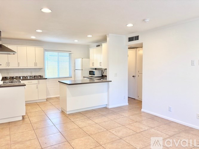 A kitchen with white cabinets and a black countertop.
