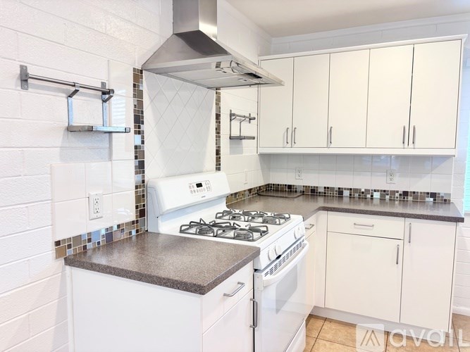 A kitchen with white cabinets and a black countertop.