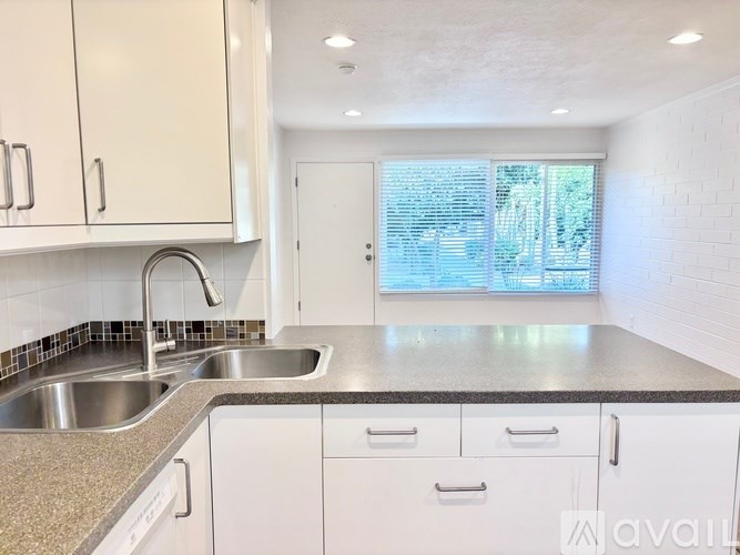 A kitchen with white cabinets and a granite countertop.