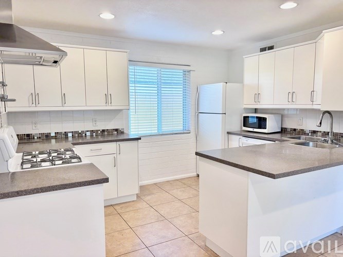 A kitchen with white cabinets and a stove top oven.
