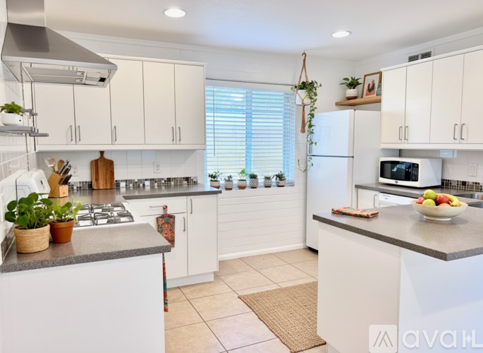 A kitchen with white cabinets and a grey countertop.