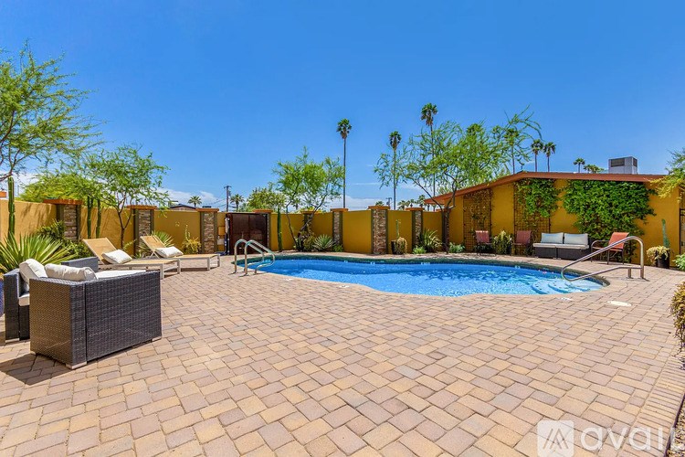 A pool surrounded by a patio and a wall with plants on it.
