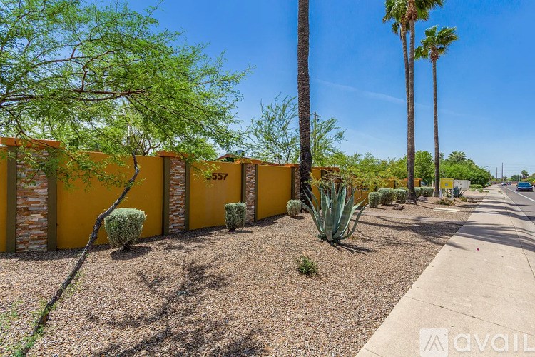 A row of yellow houses with trees and bushes in front.