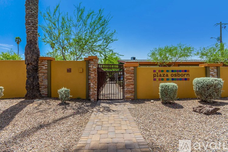 The image shows a yellow building with a sign that reads "plaza oshorn" and a gate in front of it.