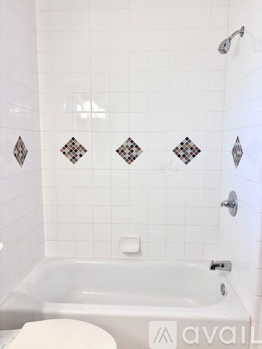 A white tiled bathroom with a jacuzzi tub and toilet.