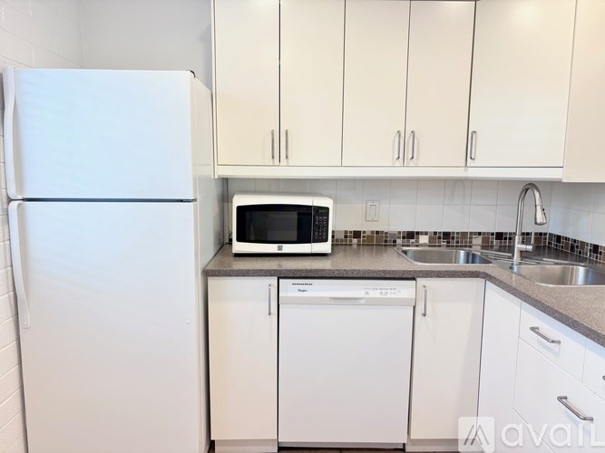 A white refrigerator stands next to a white dishwasher in a kitchen.
