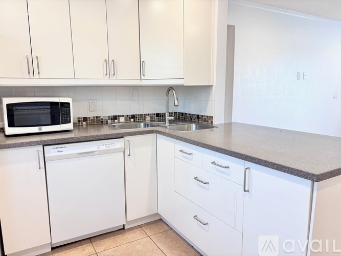 A kitchen with white cabinets and a black microwave.