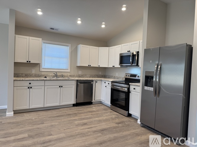 A kitchen with white cabinets and a stainless steel refrigerator.