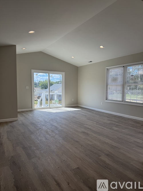 A spacious room with wooden flooring and a large window.