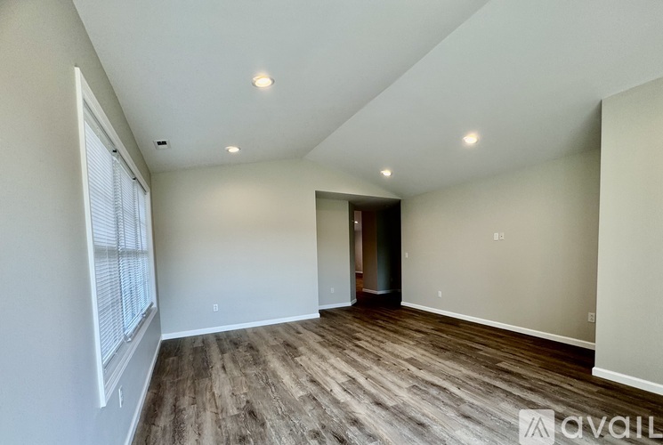 A room with wooden flooring and a window on the left side.