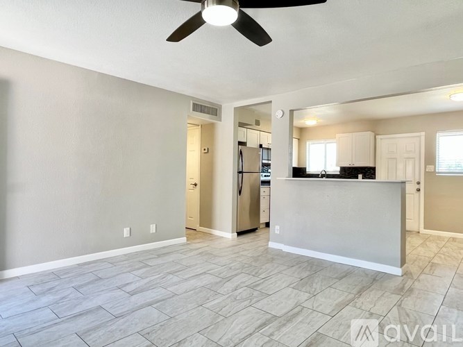 A spacious living room with a kitchen in the background.