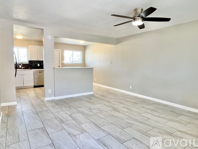 A spacious room with a ceiling fan and tiled flooring.