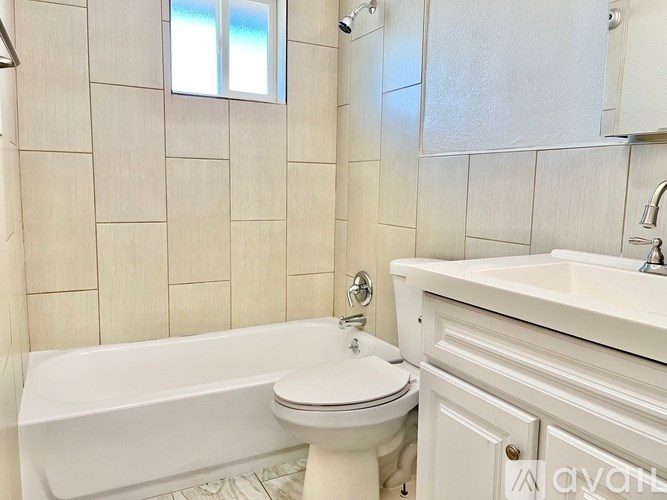 A white bathroom with a tub, toilet and sink.