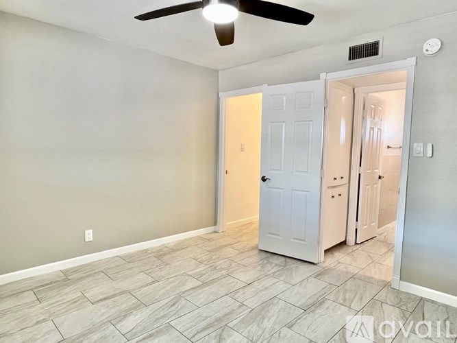 A room with a ceiling fan and a door leading to another room.