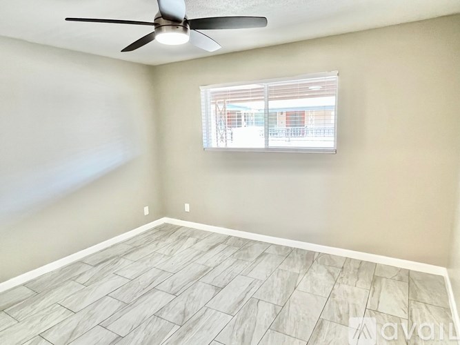 A room with a ceiling fan and a window with blinds.