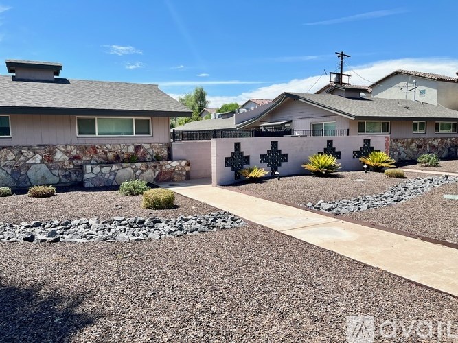 A house with a stone wall and a pathway leading to it.