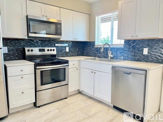 A kitchen with white cabinets and a black countertop.