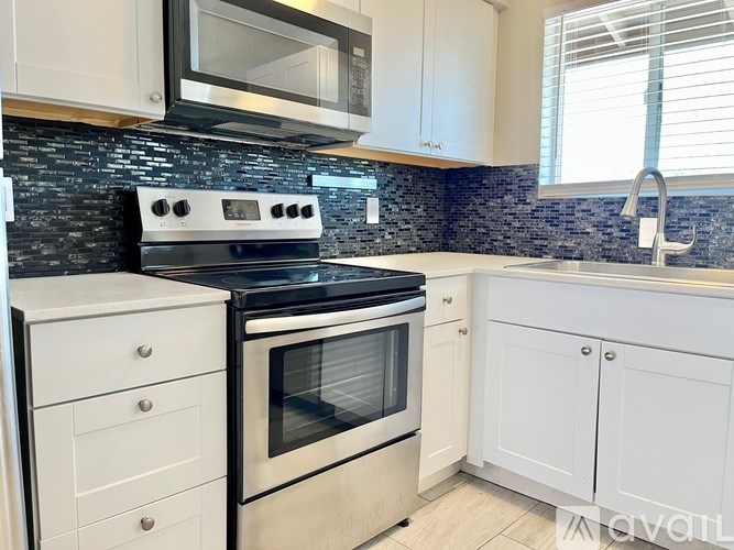 A kitchen with a black stove top oven and white cabinets.