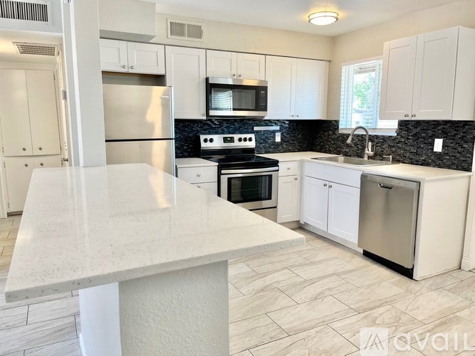 A kitchen with white cabinets and a marble countertop.