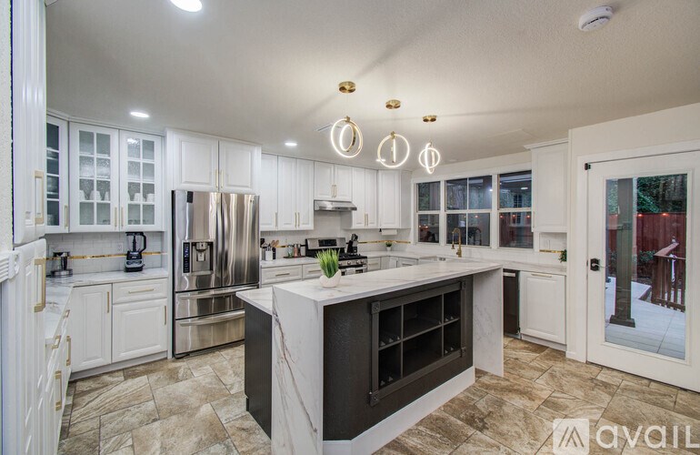 A kitchen with a marble island and stainless steel appliances.