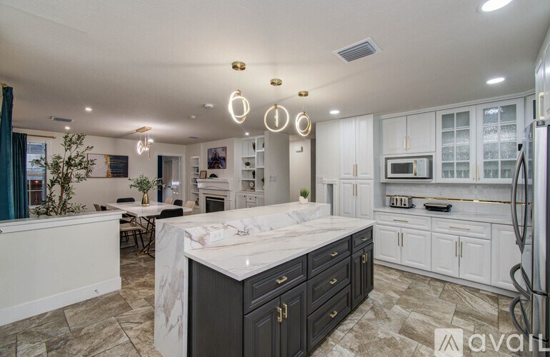 A kitchen with a marble island and white cabinets.