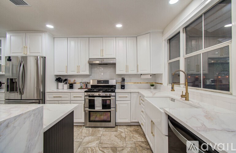 A kitchen with white cabinets and marble countertops.