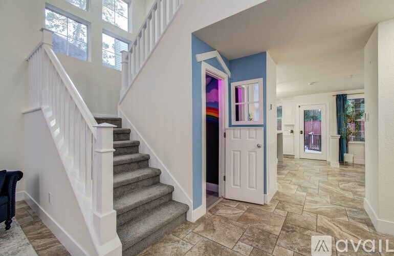 A hallway with a staircase and a door with a rainbow window.
