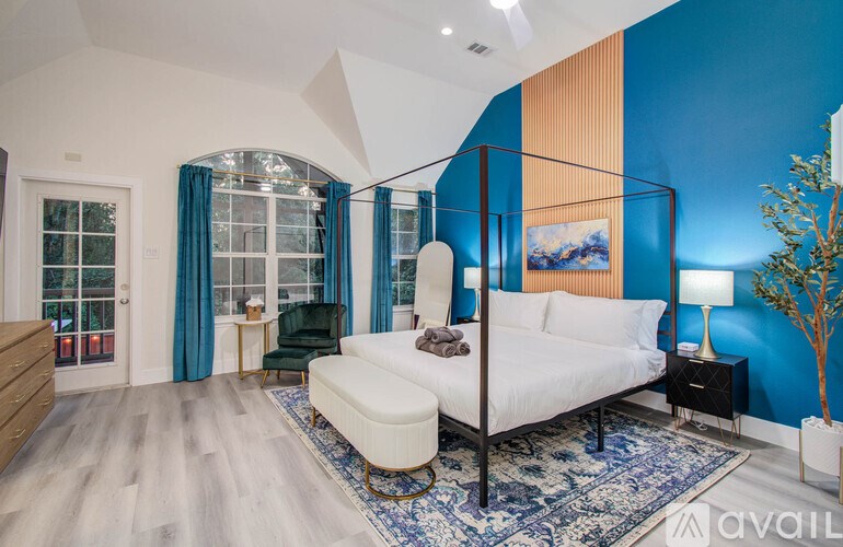 A bedroom with a white bed and a blue rug.