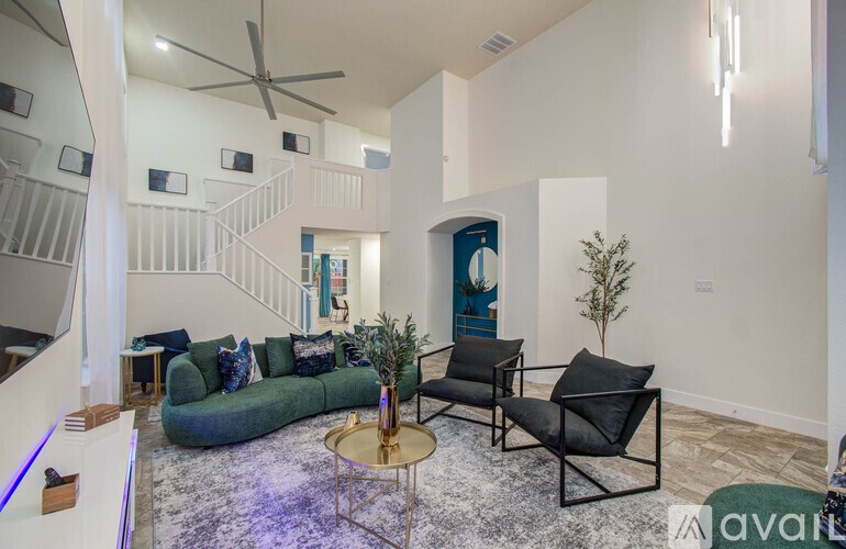A living room with a green couch, a black chair, and a small table with a plant on it.