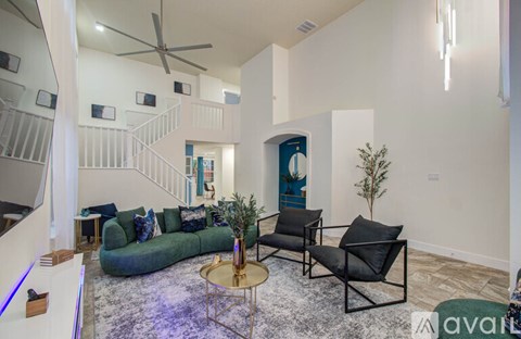 A living room with a green couch, a black chair, and a small table with a plant on it.