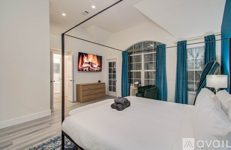 A bedroom with a large bed and a flat screen TV mounted on the wall.