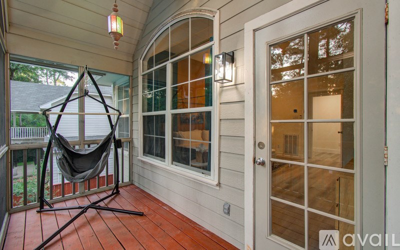 A hammock is strung up on a stand on a wooden porch.