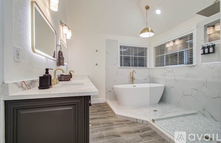 A modern bathroom with a white marble floor and a white freestanding bathtub.