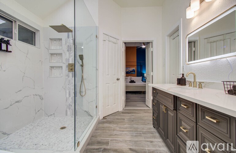 A bathroom with a walk-in shower and a vanity with a mirror.