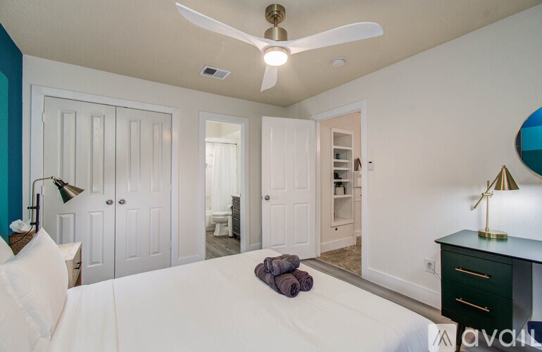 A bedroom with a bed, dresser, and a ceiling fan.