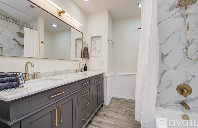 A bathroom with a marble countertop and a shower with a white curtain.