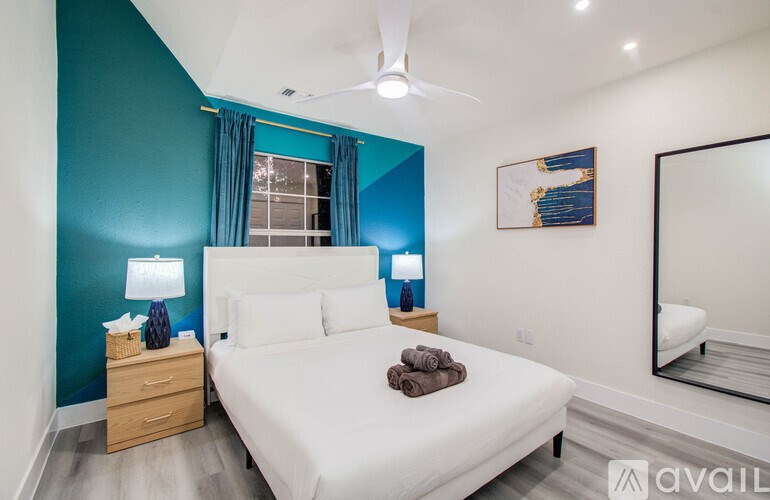 A bedroom with a white bed and a ceiling fan.